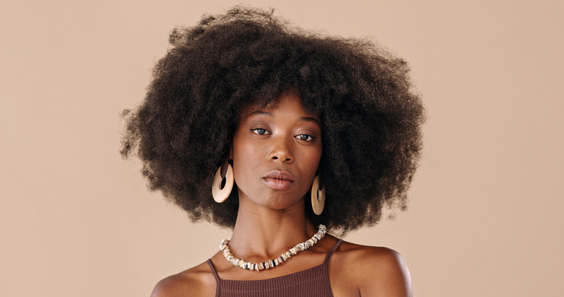Black woman afro, portrait and face in confident beauty and fashion style against a studio background. Beautiful isolated African American female proud model with necklace, jewelry and hairstyle