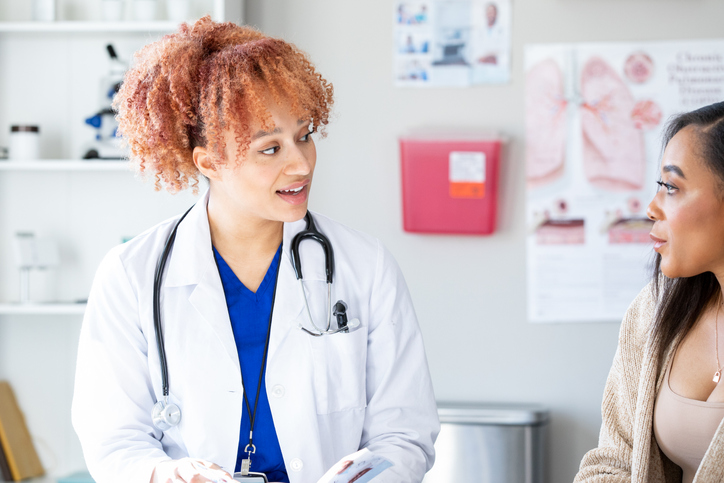 Young female doctor discusses health concerns with patient during appointment and types of health insurance plans