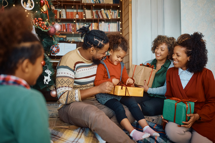 Happy black extended family opening Christmas presents at home.