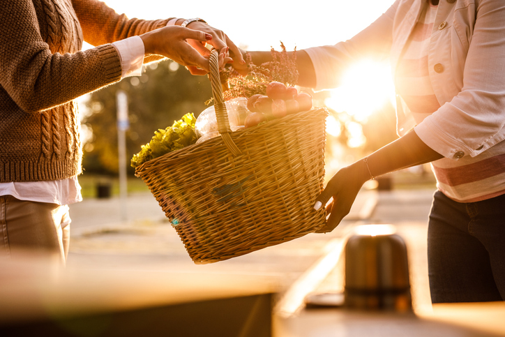 Customer receiving a basket with groceries from the service person at the curbside pickup