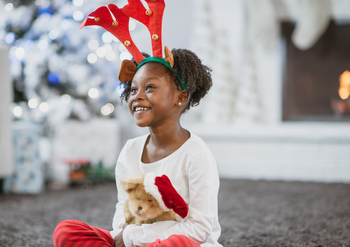 African Girl Playing with her New Christmas Teddy Bear enjoying stocking stuffers