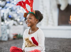 African Girl Playing with her New Christmas Teddy Bear enjoying stocking stuffer ideas