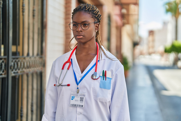 African american woman doctor standing with serious expression at street