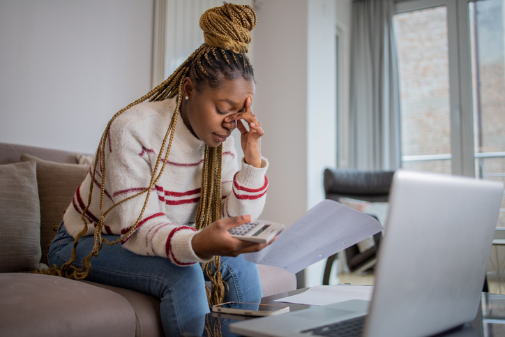 Young woman using calculator while going through bills and home finances