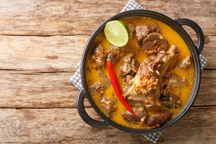 Indonesian food gulai kambing goat curry spicy stew closeup on the wooden table. Horizontal top view