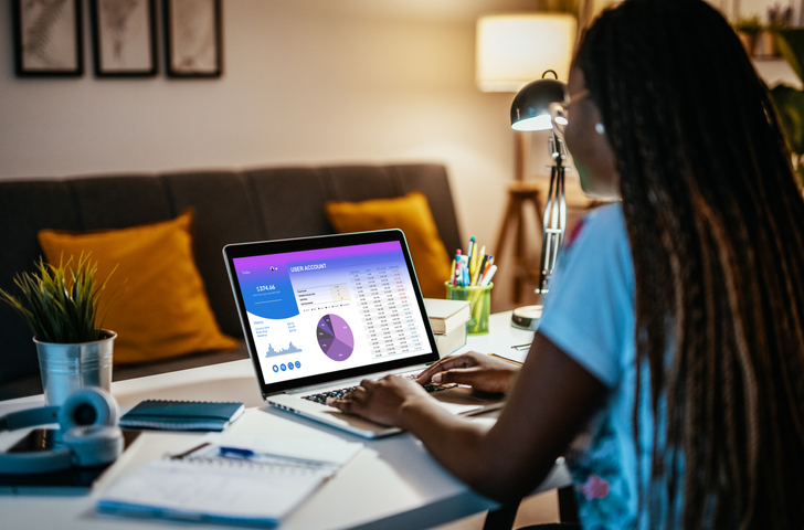African braided hair woman using online banking at home for personal finances and small investment during recession