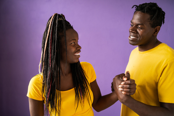 Portrait of smiling Afro american couple standing in front of purple background