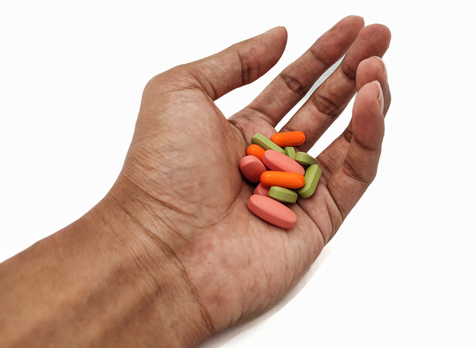 Hand holding a lot of pills on the palm on isolated white background, immunity-boosting supplements