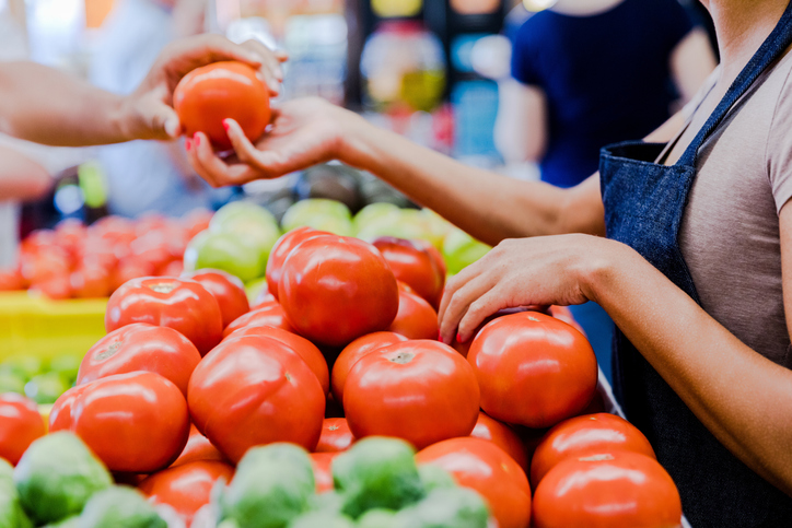 Unrecognizeable employee holding a tomato