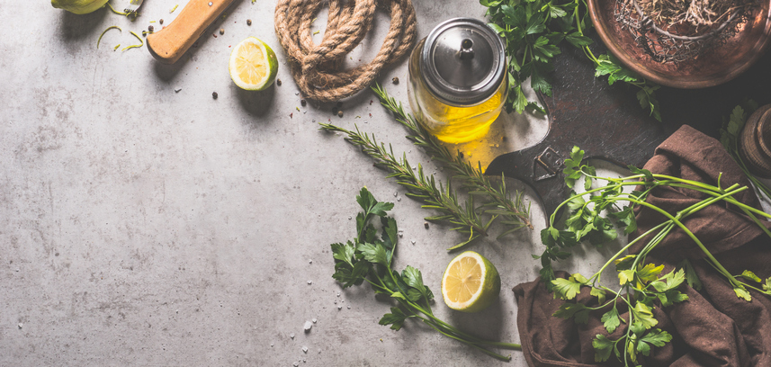 Healthy food background banner with fresh herbs, lemon, olive oil and kitchen utensils