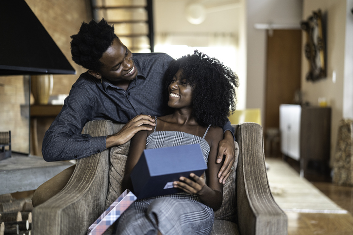 Husband making a surprise giving a present to his wife at home
