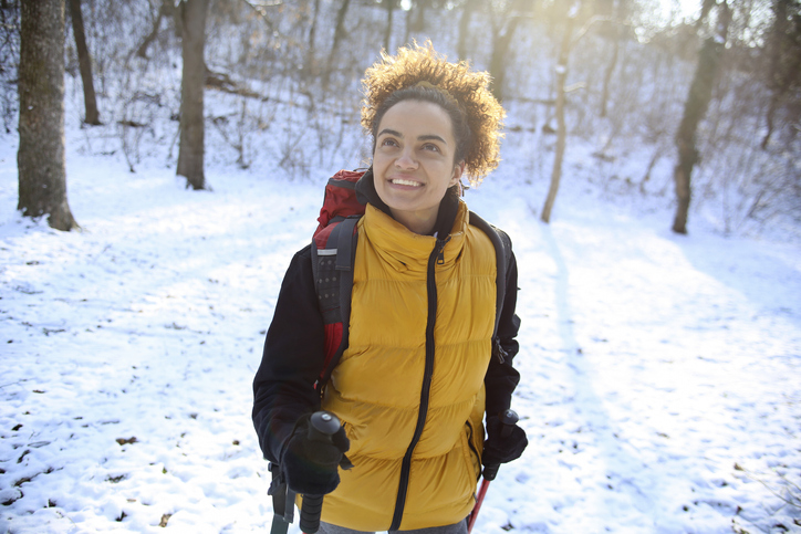 Smiling young woman hiking in nature during the winter