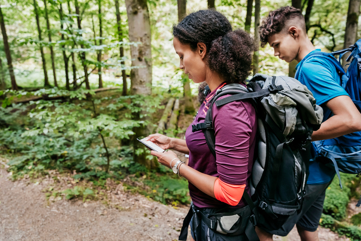 Mother Looking At Smartphone While Out Hiking With Sons