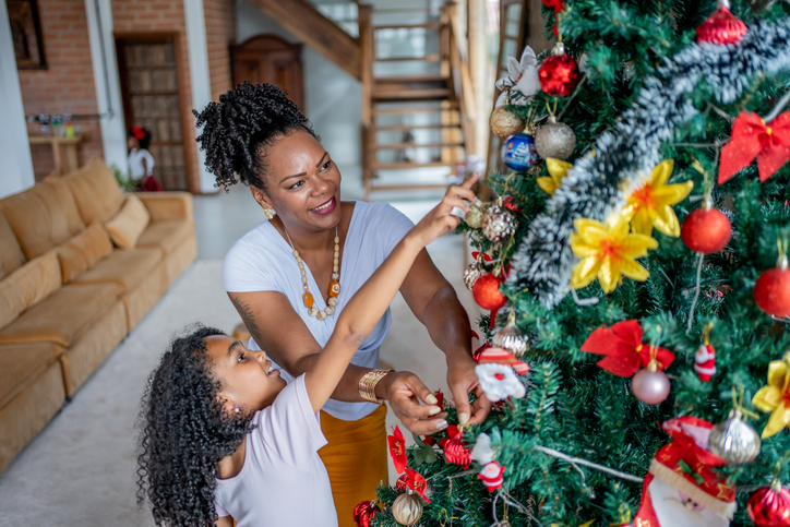 Mother and daughter decorating Christmas tree with ethical holiday decor
