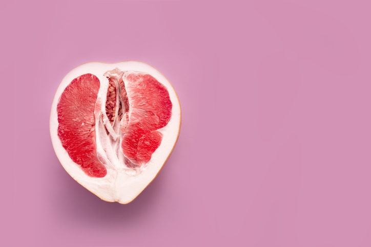 A half peeled grapefruit on a pink colored background. Minimal still life
