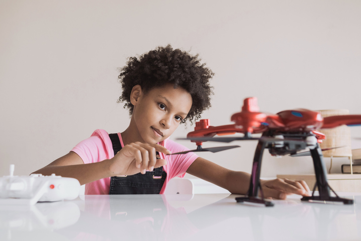 Little girl child playing with drone at home enjoying STEM toys