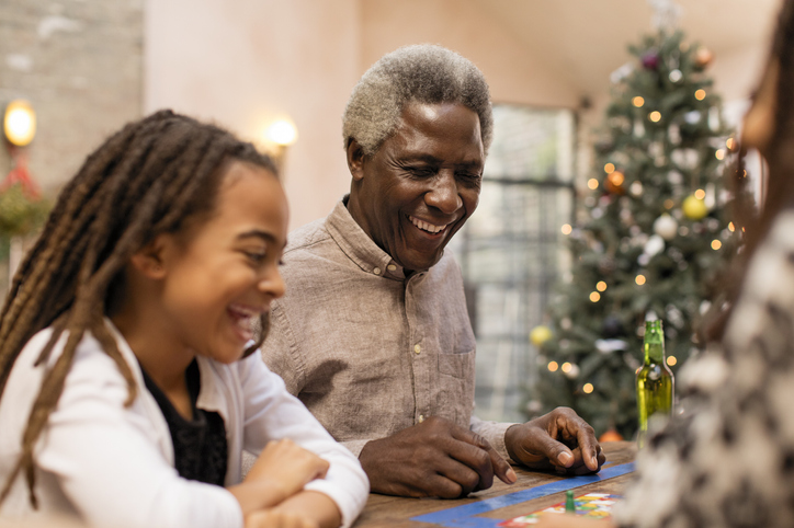 Smiling grandfather and granddaughter playing board game