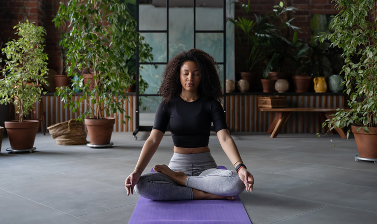 Closeup Young black woman practicing yoga in relax position while sitting on mat at gym fitness studio, Concept of relaxation and meditation. Copy space, mock up, template
