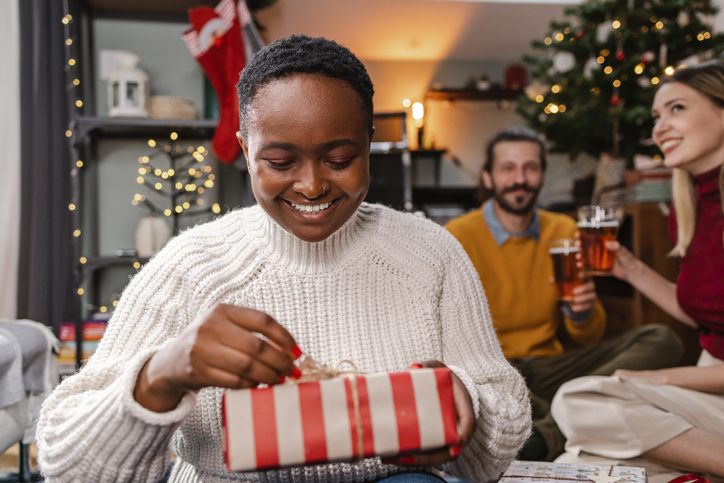 African-American young unwrapping Christmas present in the living room