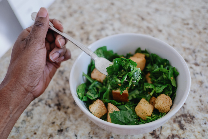 Woman Eats Spinach Salad in Kitchen