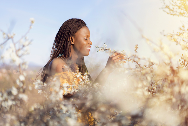 Young woman enjoying the orchard in bloom, smelling the flowers