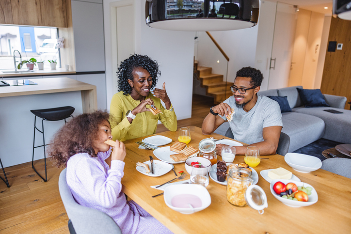 Black Family Smiling And Eating Breakfast In A Cosy Modern Apartment learning about eating healthier as a family