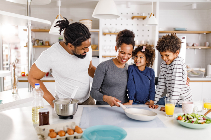Happy black family making pancakes in the kitchen.
