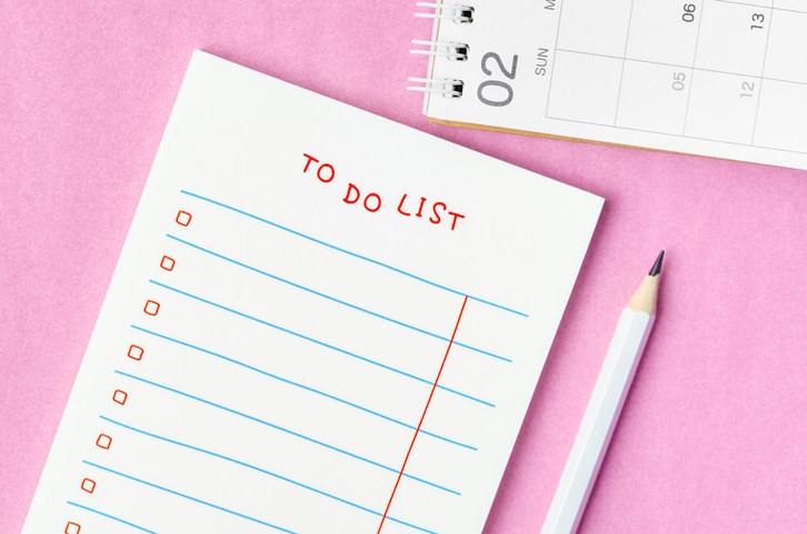 A Blank To do list in notepad and desk calendar with wooden pencil on pink background. Top view