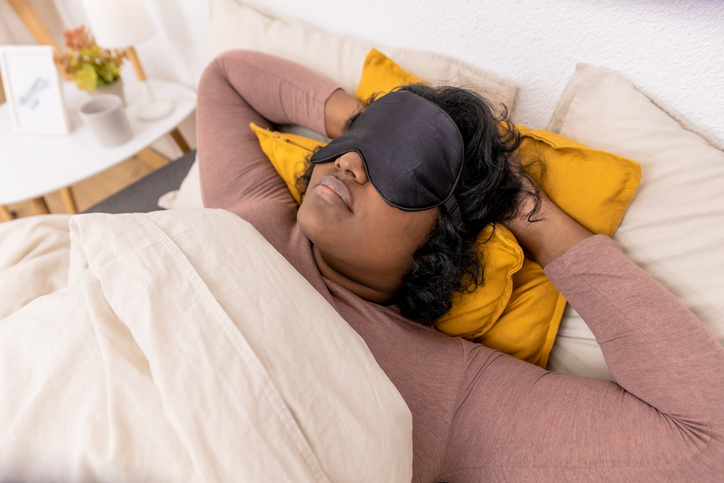 Relaxed woman sleeping with a black eye mask in the bed at home, zen