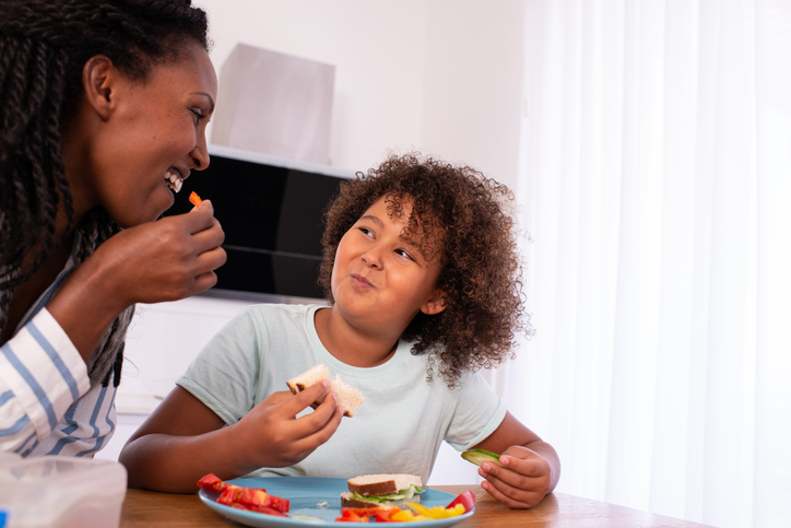 Satisfied school kid and mother eating healthy breakfast.