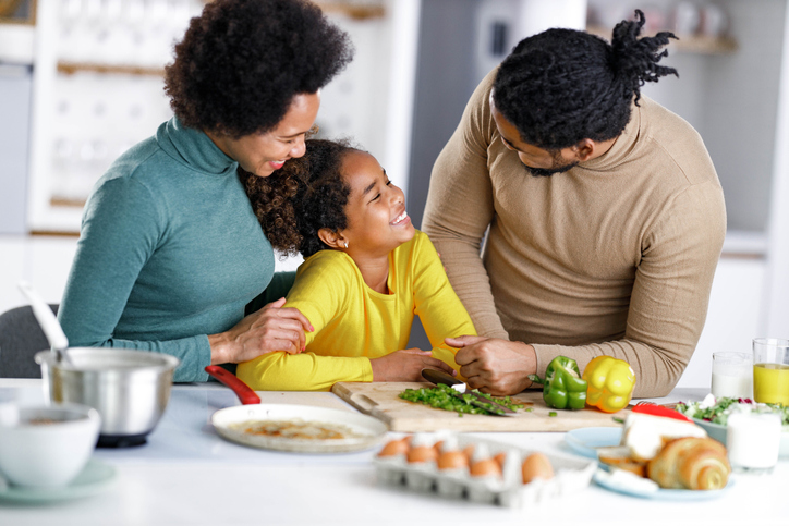 Happy African American family talking while preparing food in the kitchen for healthy eating
