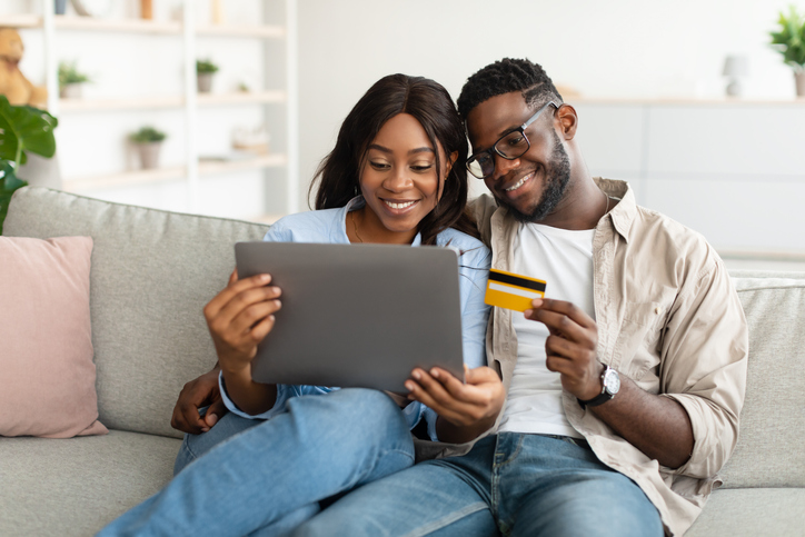 Black couple using pc and debit credit card at home