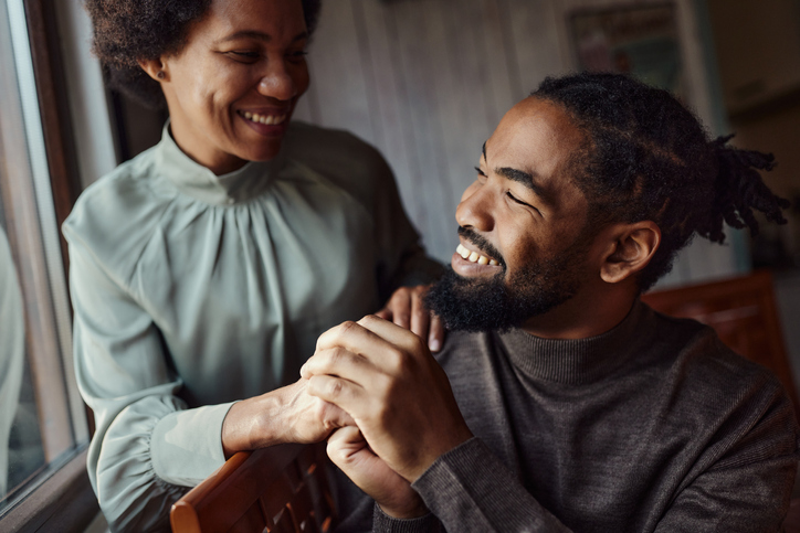 Happy black couple holding hands and talking at home.