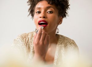 Glamorous Black woman applying red lipstick