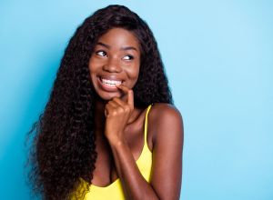 Portrait of attractive cheerful wavy-haired girl biting nail thinking copy space isolated over vibrant blue color background