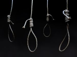 Dark scary hanging nooses on black background.