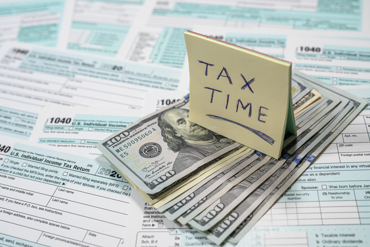 US tax forms 1040 with dollar bills and inscriptions spread out on a spacious table.
