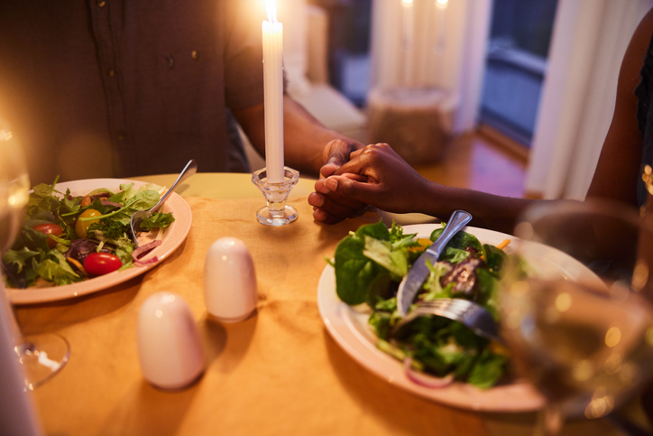 Loving couple holding hands over a candlelit dinner together