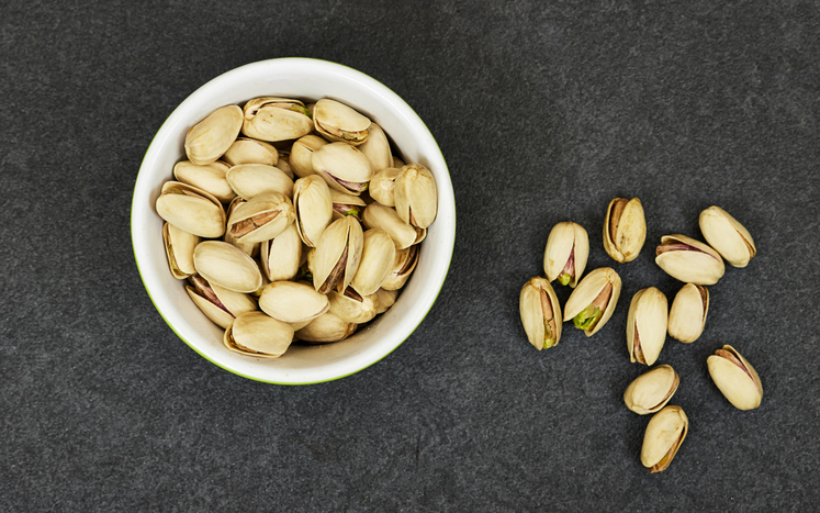 Pistachios in bowl on grunge gray and black background