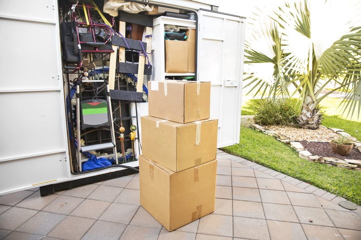 Moving Series: Packing cartons on driveway with full moving container