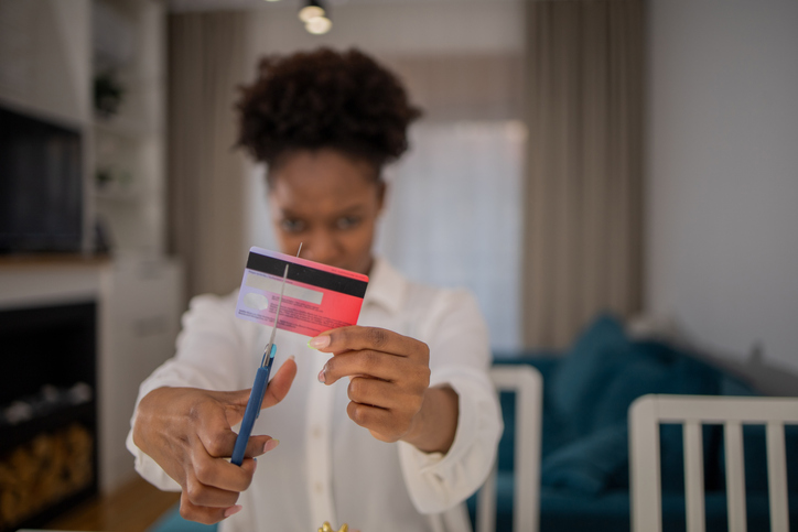 Young woman is cutting up a credit card with scissors