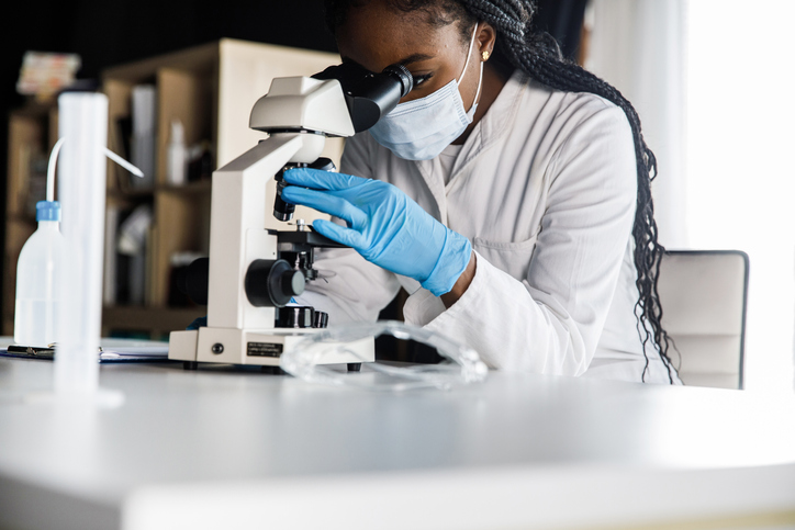 Copy space shot of female scienitst analyzing a sample under a microscope while doing research