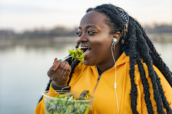 An African American woman eating fresh salad for lunch