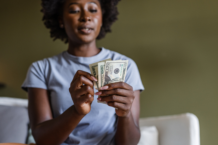 Portrait of a worried young woman counting money