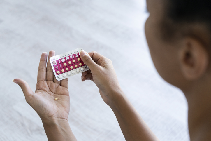 Young woman holding birth control pills