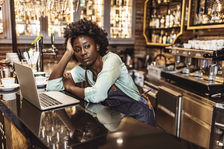 Young bartender leaning on bar counter thoughtful