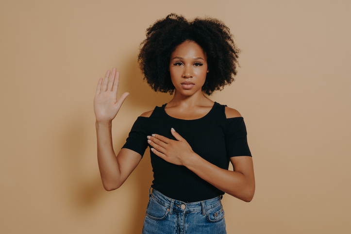 Dark skinned woman wearing casual shirt and jeans , doing loyalty promise oath standing up for sexual assault survivors