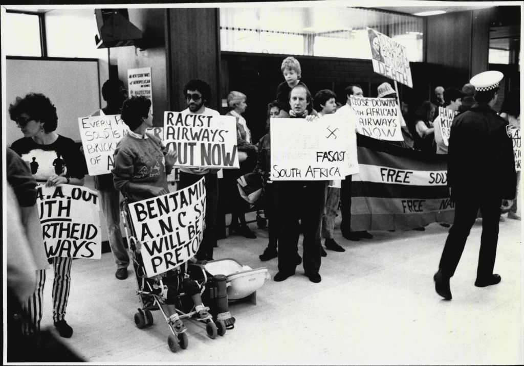 Anti apartheid demonstrators inside Sydney's international airport terminal protecting against radio man John Tingle's trip to South Africa.