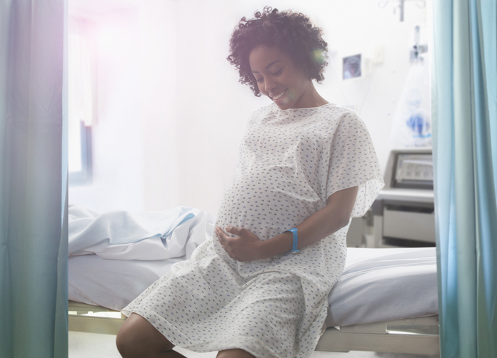 Pregnant African American woman holding her stomach in hospital