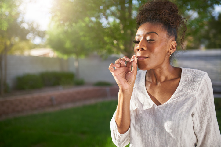 happy african american woman smoking cannabis joint in yard